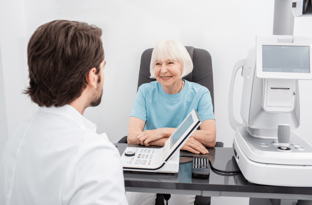 A male optometrist talks with an older female patient before he examines her eyes