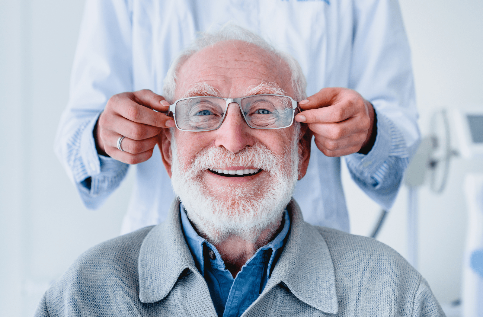An older man having new glasses adjusted to his face by an optician