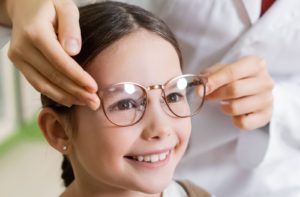A young girl receives glasses from her optician as a method to treat myopia progression