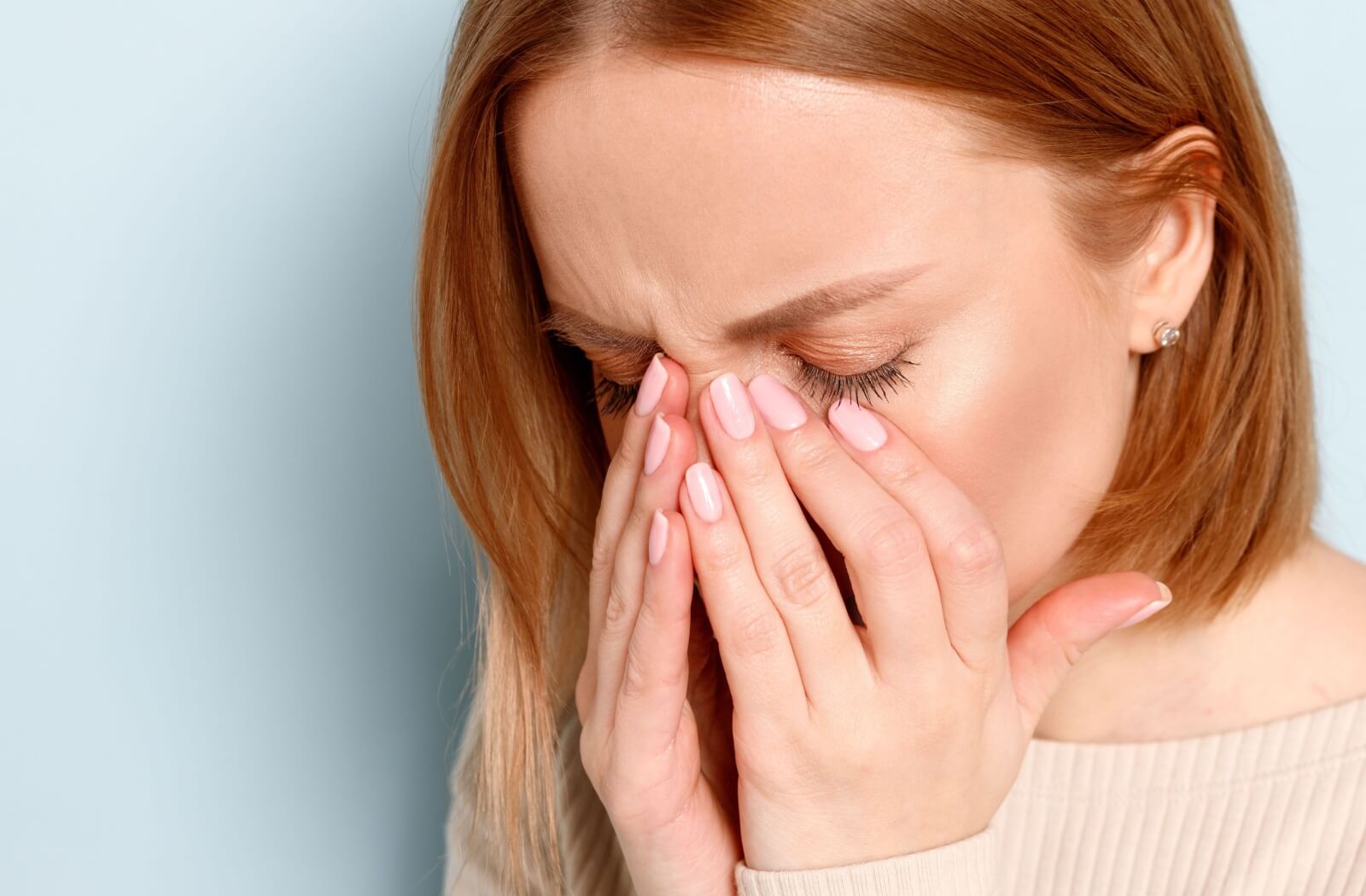 A young woman rubbing her eyes due to smoke irritation.