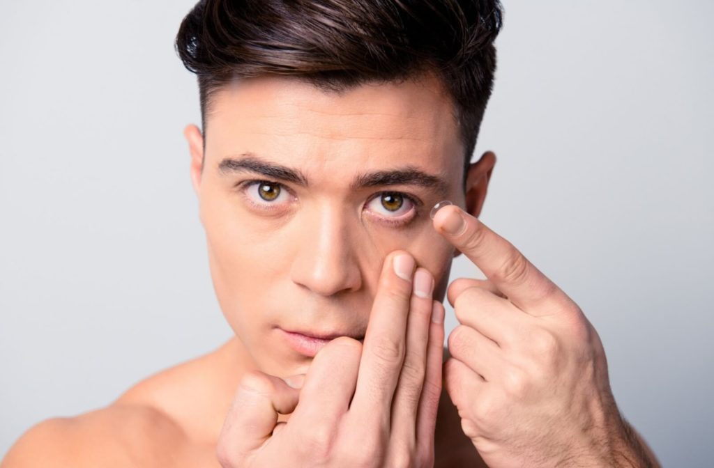 Teenaged boy puts in a contact lens.