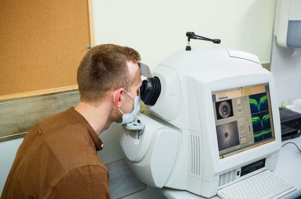 A patient rests on an OCT machine that takes cross-sectional scans of their optic nerve.