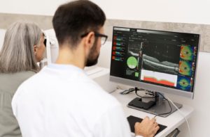 An eye doctor examining a patient's eye condition on a monitor during an eye exam.