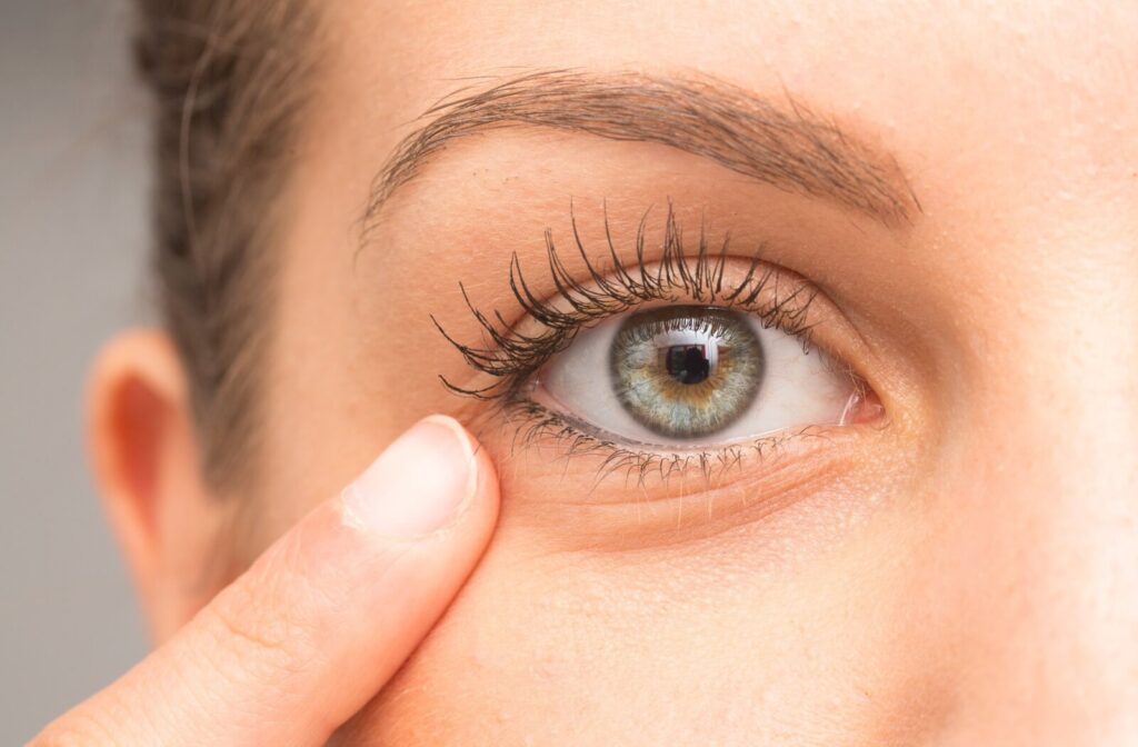 Close-up of an eye with a finger gently touching the skin below the lower eyelid.